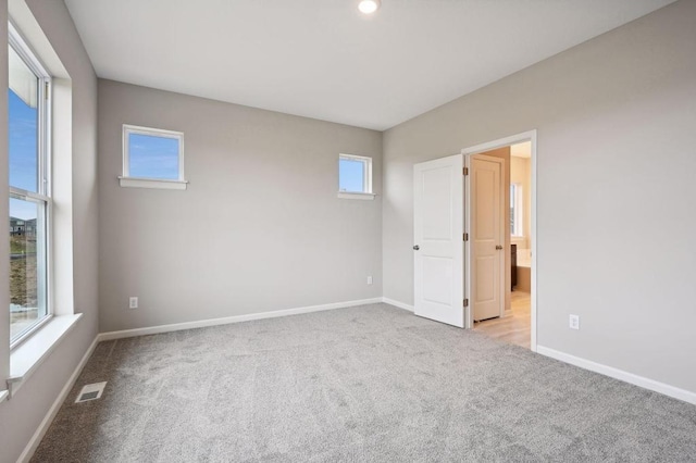 spare room featuring visible vents, baseboards, and light colored carpet