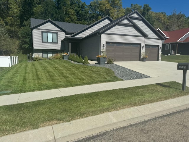 view of front of house featuring a garage, driveway, fence, and a front yard