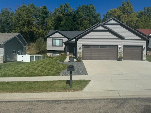 view of front of house with an attached garage, a front yard, fence, stone siding, and driveway