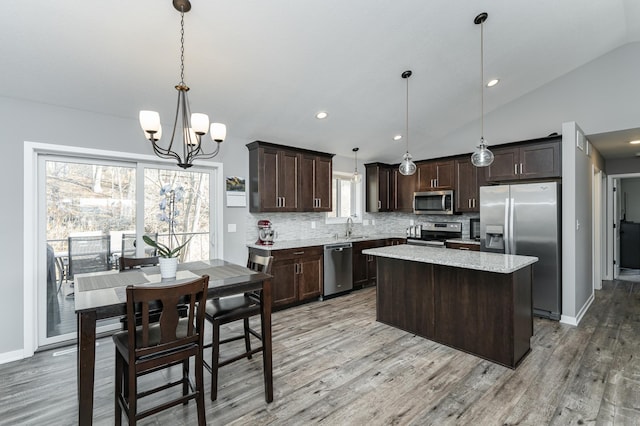 kitchen with tasteful backsplash, appliances with stainless steel finishes, a center island, vaulted ceiling, and dark brown cabinets