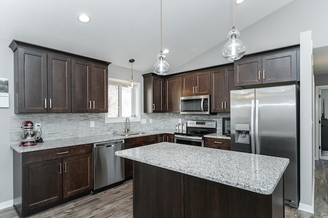 kitchen with stainless steel appliances, lofted ceiling, a sink, a kitchen island, and dark brown cabinets