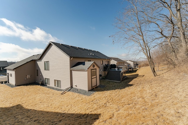 view of side of property with a deck and roof with shingles