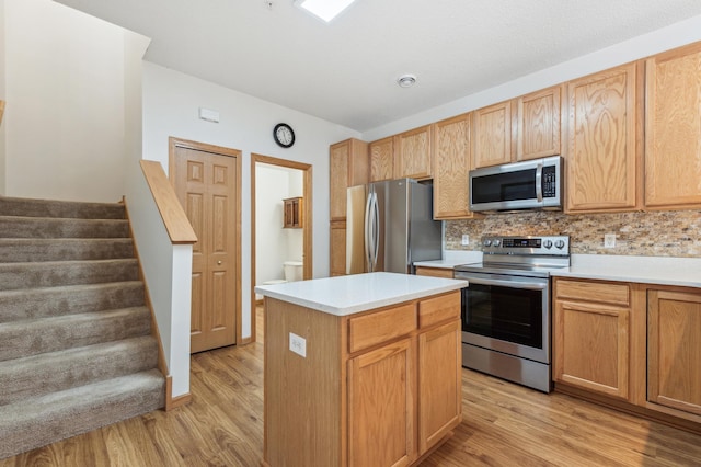 kitchen featuring appliances with stainless steel finishes, a center island, light wood-type flooring, and decorative backsplash