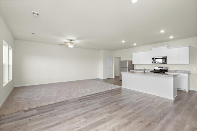 kitchen with white cabinetry, a kitchen island with sink, ceiling fan, stainless steel appliances, and light hardwood / wood-style flooring