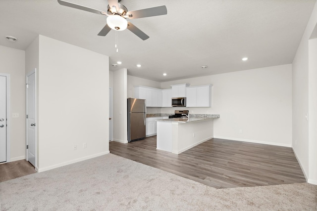 kitchen with ceiling fan, appliances with stainless steel finishes, white cabinetry, carpet, and kitchen peninsula