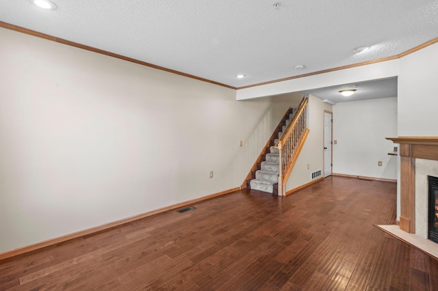 unfurnished living room featuring dark hardwood / wood-style flooring, ornamental molding, and a textured ceiling