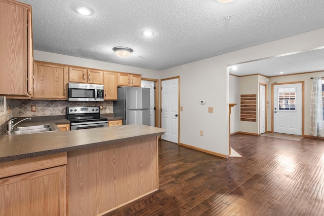 kitchen with sink, backsplash, stainless steel appliances, dark wood-type flooring, and a textured ceiling