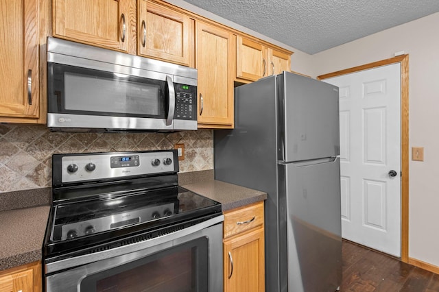 kitchen featuring appliances with stainless steel finishes, dark hardwood / wood-style floors, a textured ceiling, and decorative backsplash