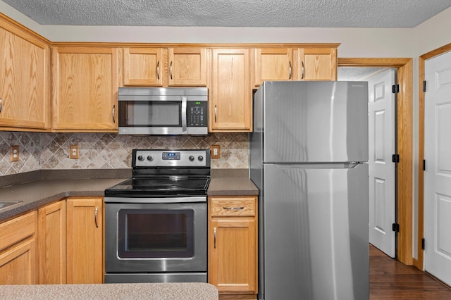 kitchen featuring appliances with stainless steel finishes, dark hardwood / wood-style flooring, decorative backsplash, and a textured ceiling