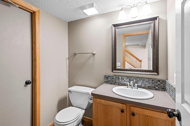 bathroom with tasteful backsplash, vanity, toilet, and a textured ceiling