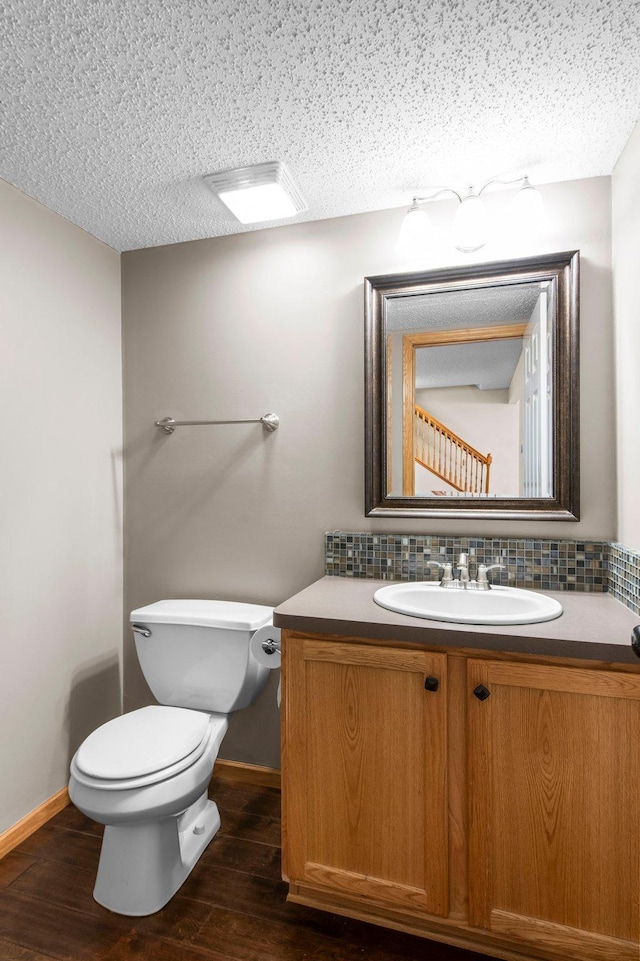 bathroom with vanity, hardwood / wood-style floors, backsplash, and a textured ceiling