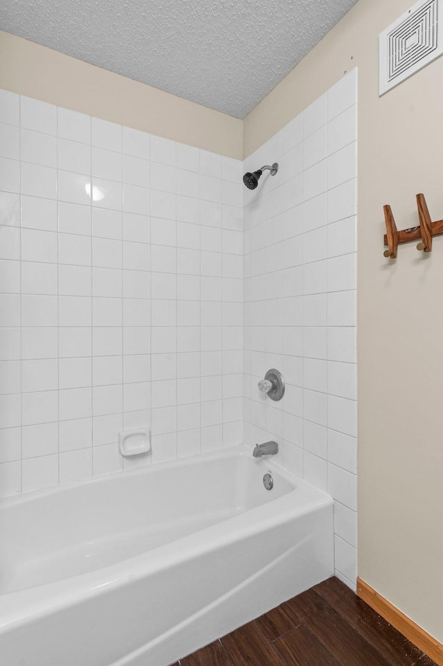 bathroom with tiled shower / bath combo, wood-type flooring, and a textured ceiling