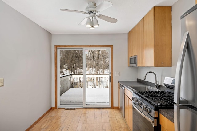 kitchen with ceiling fan, appliances with stainless steel finishes, sink, and light hardwood / wood-style floors