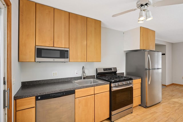 kitchen featuring ceiling fan, appliances with stainless steel finishes, sink, and light wood-type flooring