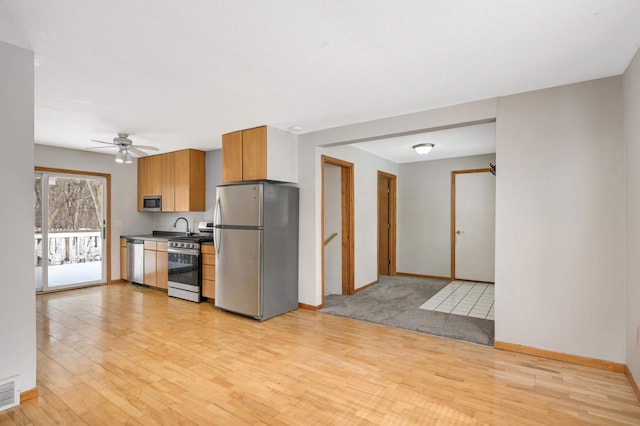 kitchen featuring ceiling fan, appliances with stainless steel finishes, and light hardwood / wood-style floors