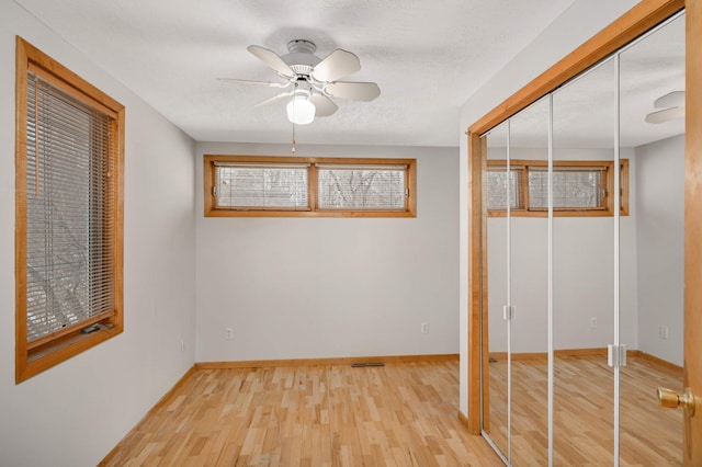 unfurnished bedroom featuring hardwood / wood-style flooring, a textured ceiling, ceiling fan, and a closet