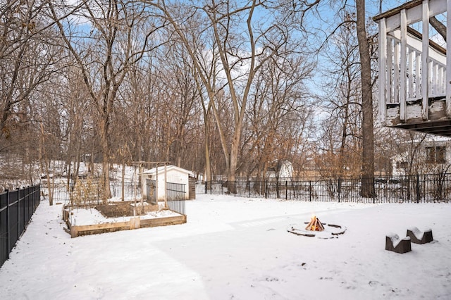 yard covered in snow featuring a storage shed and a fire pit