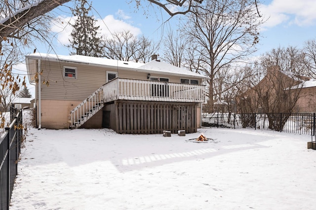 snow covered back of property with a deck