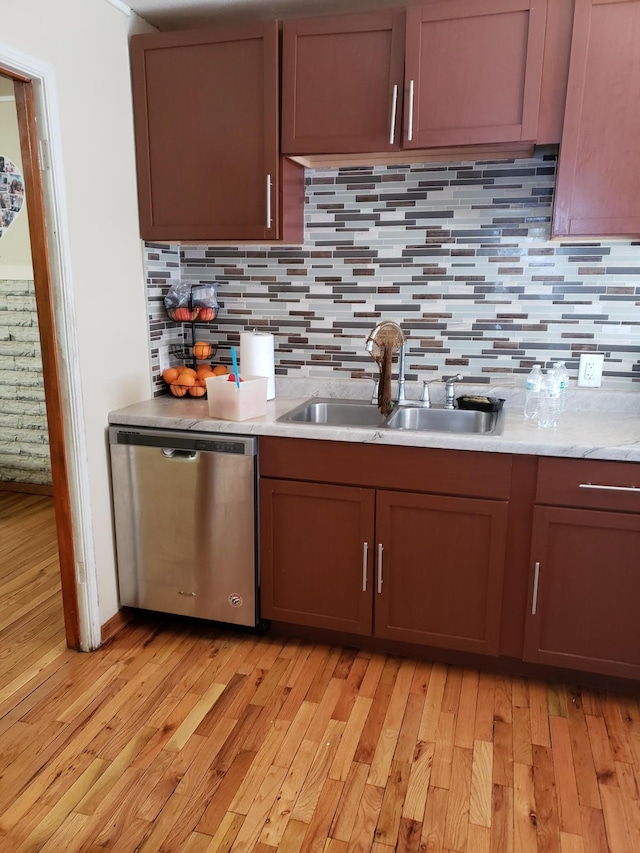 kitchen with tasteful backsplash, sink, dishwasher, and light wood-type flooring