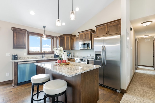 kitchen with lofted ceiling, a breakfast bar area, hanging light fixtures, a kitchen island, and stainless steel appliances