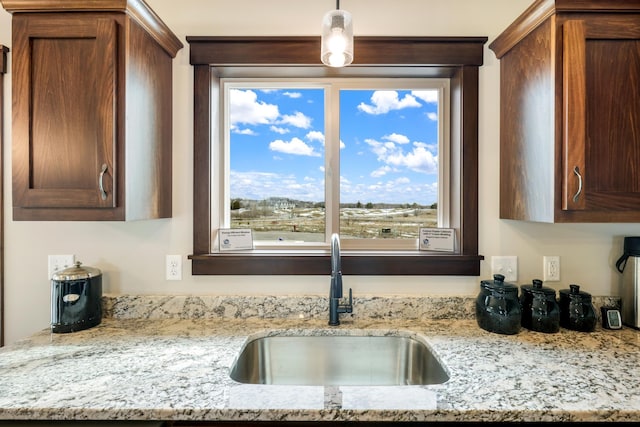 kitchen featuring sink, pendant lighting, and light stone counters