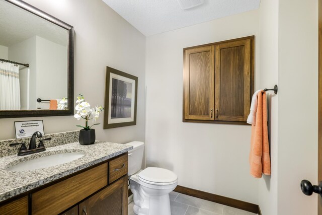 bathroom with vanity, a textured ceiling, tile patterned floors, and toilet