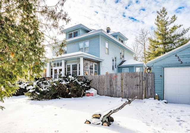 snow covered rear of property with a garage