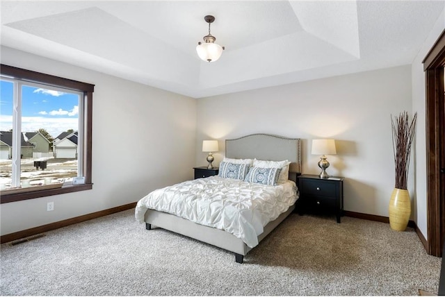 carpeted bedroom with a tray ceiling