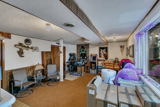 interior space featuring visible vents, a textured ceiling, carpet, and a wainscoted wall