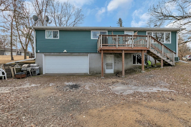 back of house with stairway, cooling unit, an attached garage, dirt driveway, and a deck