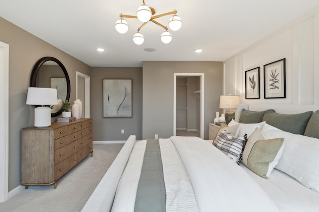 bedroom with light colored carpet, a spacious closet, ceiling fan with notable chandelier, and a closet