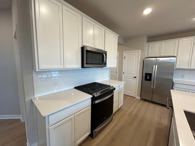 kitchen featuring stainless steel appliances, light hardwood / wood-style floors, decorative backsplash, and white cabinets