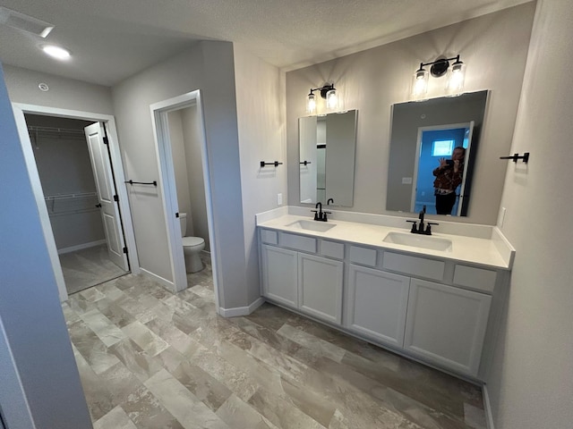 bathroom with vanity, toilet, and a textured ceiling