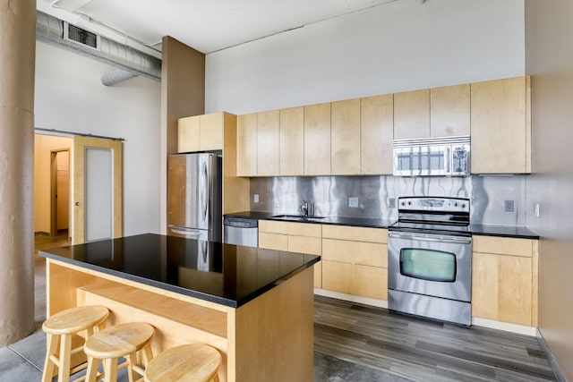 kitchen featuring a center island, light brown cabinets, appliances with stainless steel finishes, a towering ceiling, and decorative backsplash