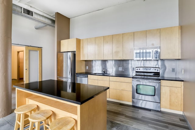 2929 Chicago Ave Unit 1216, Minneapolis, MN 55407 - kitchen featuring stainless steel appliances, light brown cabinets, a breakfast bar, dark countertops, and a high ceiling