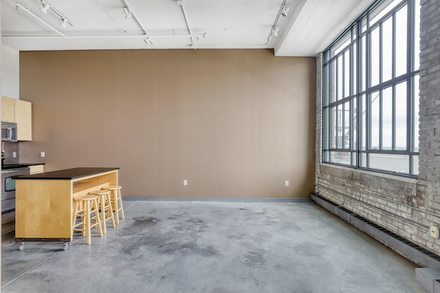 2929 Chicago Ave Unit 1216, Minneapolis, MN 55407 - kitchen with appliances with stainless steel finishes, rail lighting, concrete floors, a breakfast bar, and a baseboard radiator