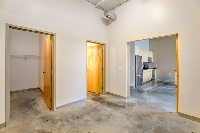 2929 Chicago Ave Unit 1216, Minneapolis, MN 55407 - unfurnished bedroom featuring freestanding refrigerator, unfinished concrete floors, a high ceiling, a walk in closet, and a closet