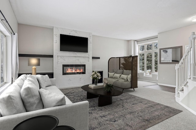 carpeted living room featuring stairs, baseboards, and a premium fireplace