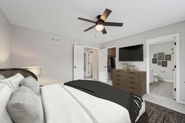 bedroom featuring visible vents, ensuite bath, ceiling fan, a spacious closet, and carpet flooring