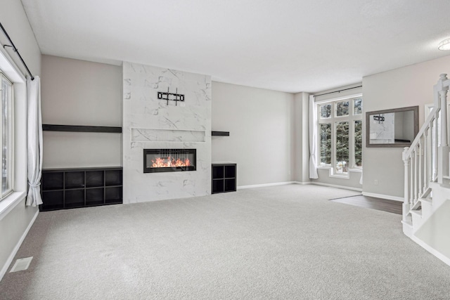 unfurnished living room with baseboards, visible vents, stairway, carpet floors, and a fireplace