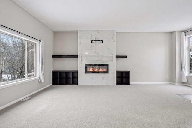 unfurnished living room featuring carpet, a fireplace, visible vents, and baseboards