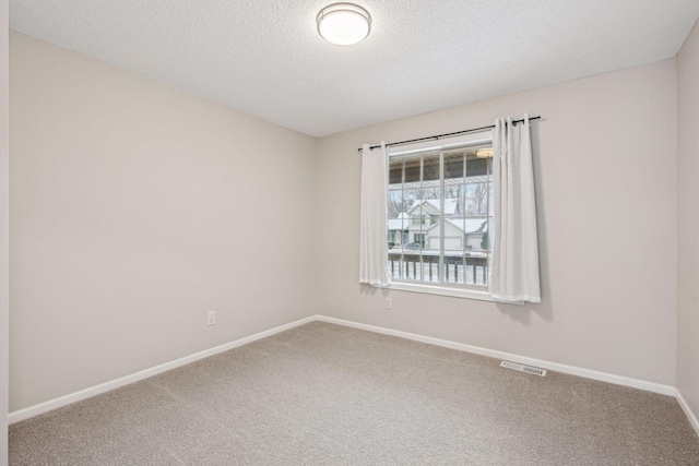 unfurnished room with a textured ceiling, carpet flooring, visible vents, and baseboards