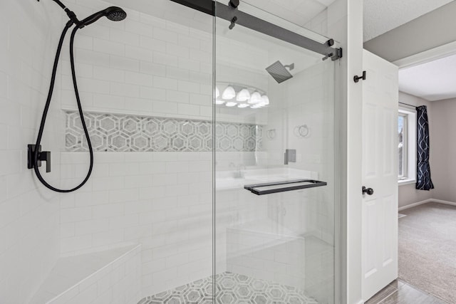 bathroom with a stall shower, a textured ceiling, and baseboards