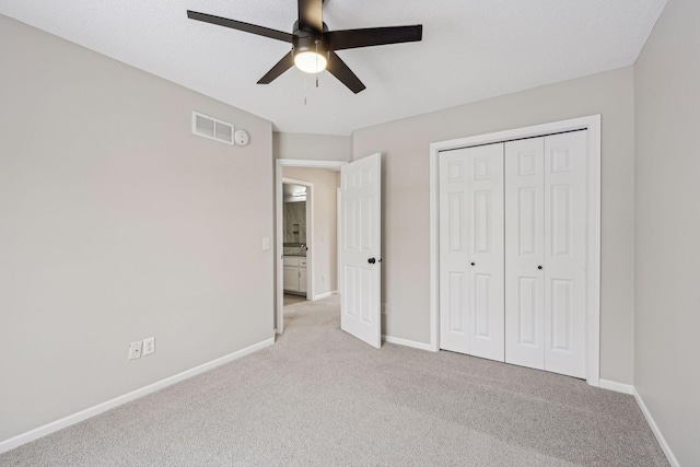 unfurnished bedroom with ceiling fan, light carpet, visible vents, baseboards, and a closet