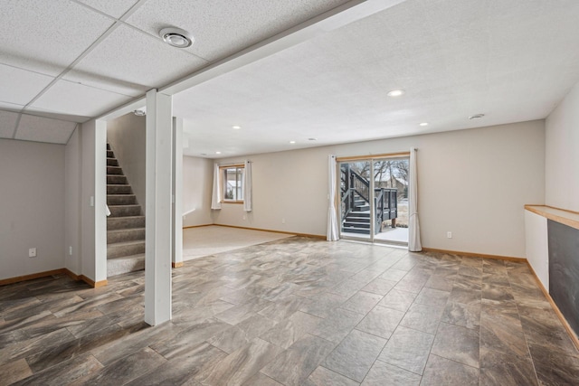 below grade area with stairway, recessed lighting, a paneled ceiling, and baseboards