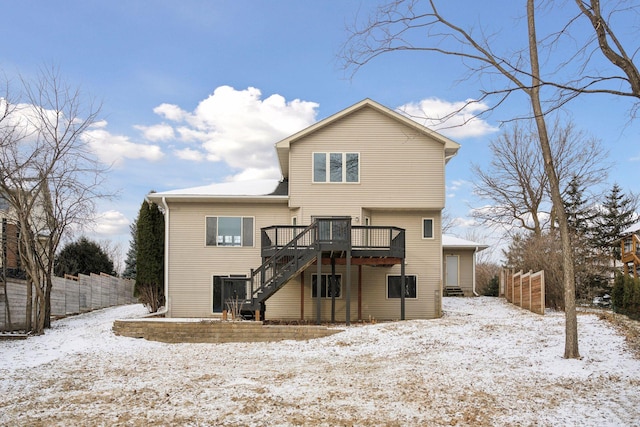 snow covered rear of property featuring fence, a wooden deck, and stairs