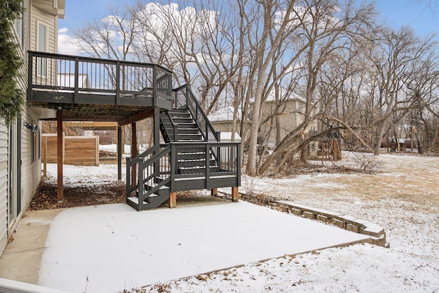 yard layered in snow featuring stairway and a wooden deck