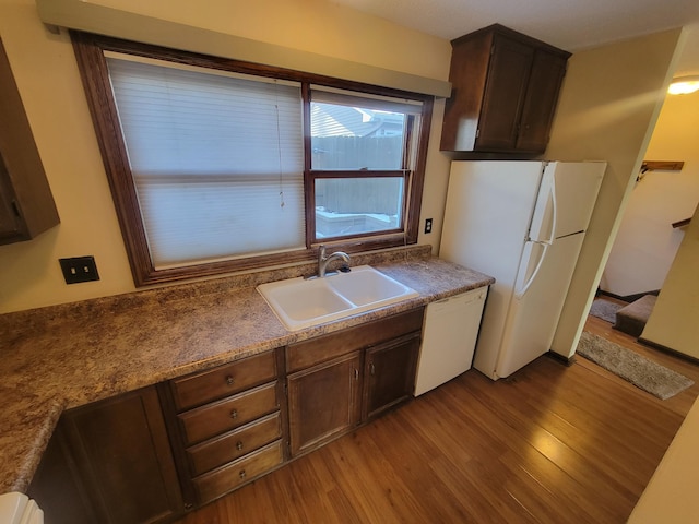 kitchen featuring sink, white appliances, light hardwood / wood-style flooring, and dark brown cabinets