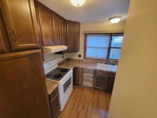 kitchen with white electric range, sink, light wood-type flooring, dark stone counters, and a textured ceiling