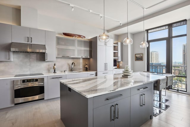 kitchen with sink, a kitchen bar, track lighting, a kitchen island, and oven